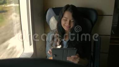年轻女子乘火车旅行时使用她的平板电脑。 旅行应用概念